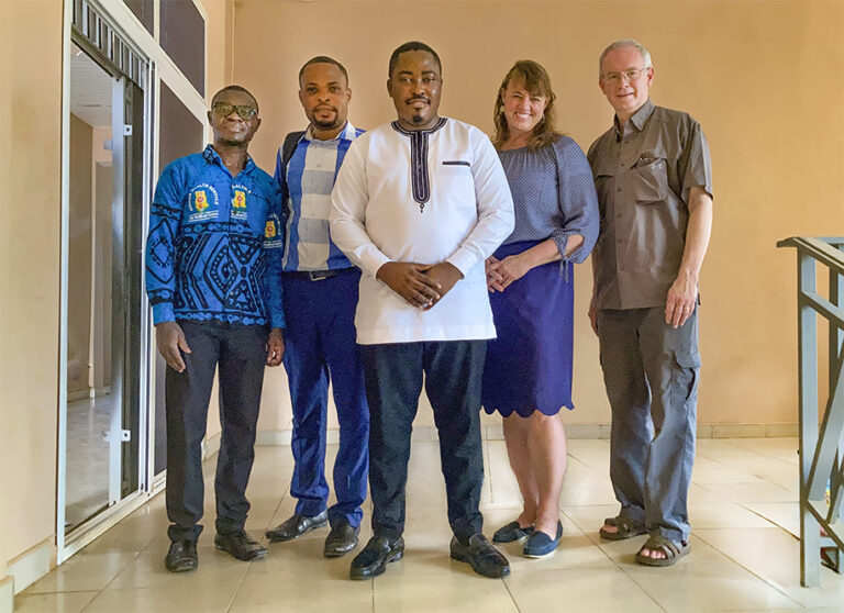 Five people standing in a line smiling at camera.